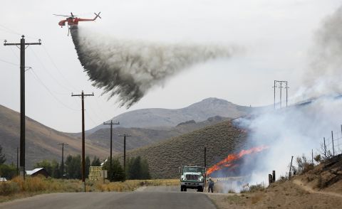 A tanker helicopter drops water as a firefighter works to douse a hot spot at Beaver Creek on August 17. 