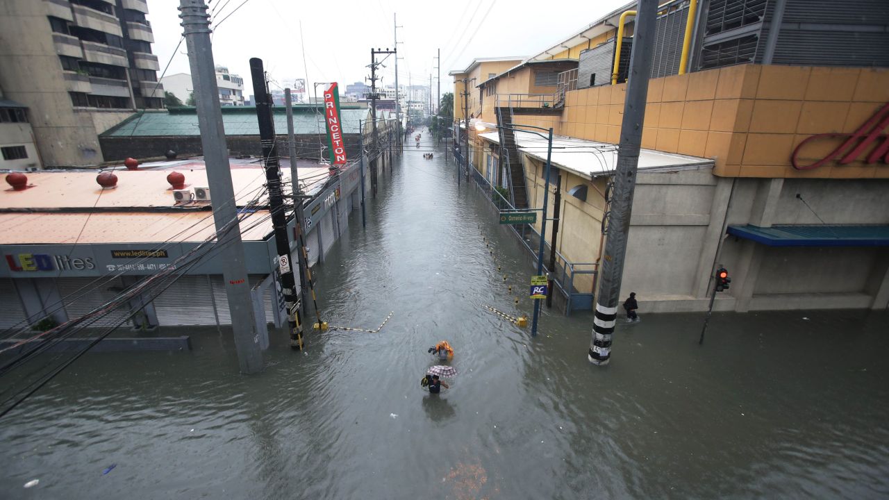 People wade through a flooded street in Makati on August 20.