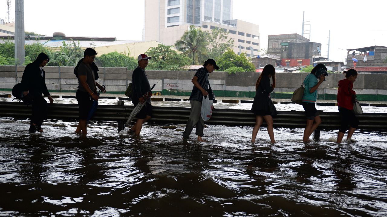 People walk along a flooded highway as heavy rains hit Manila on August 20.