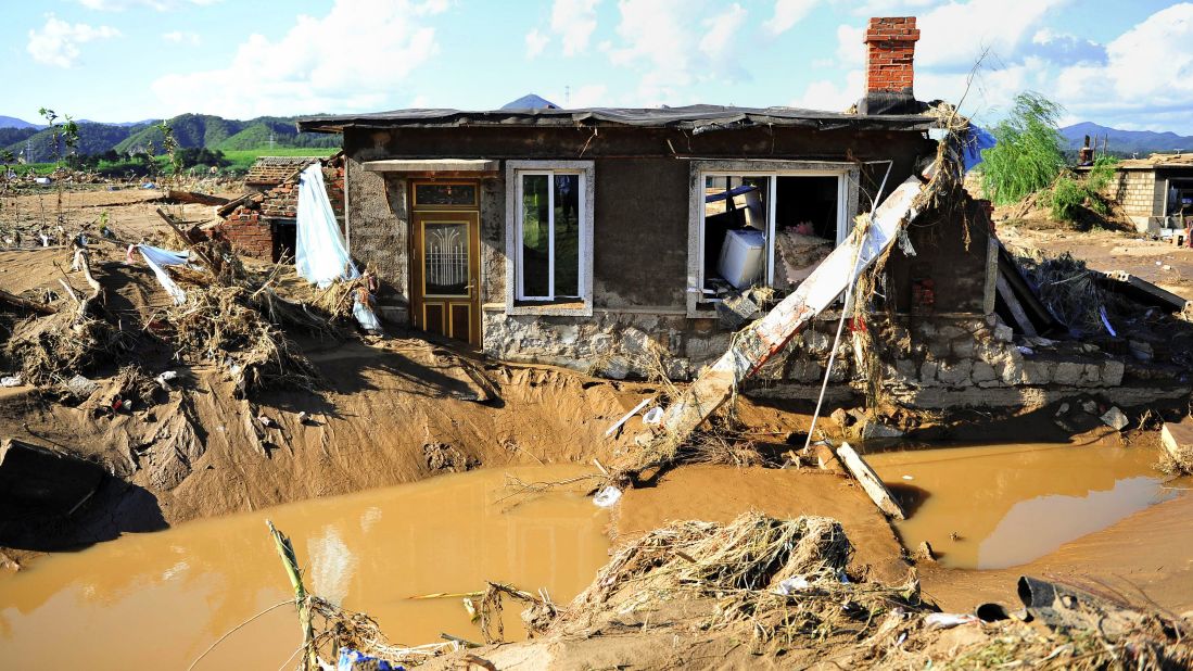 A damaged house sits in mud and floodwater in China's Liaoning province on August 19.