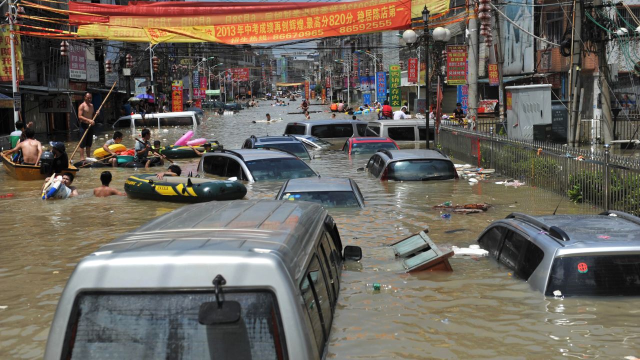 People walk through debris and vehicles submerged in floodwaters in Shantou on August 19.