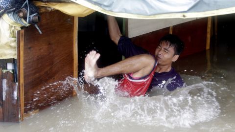 A man falls as he tries to fix the roof of his flooded home in Binakayan on August 19.