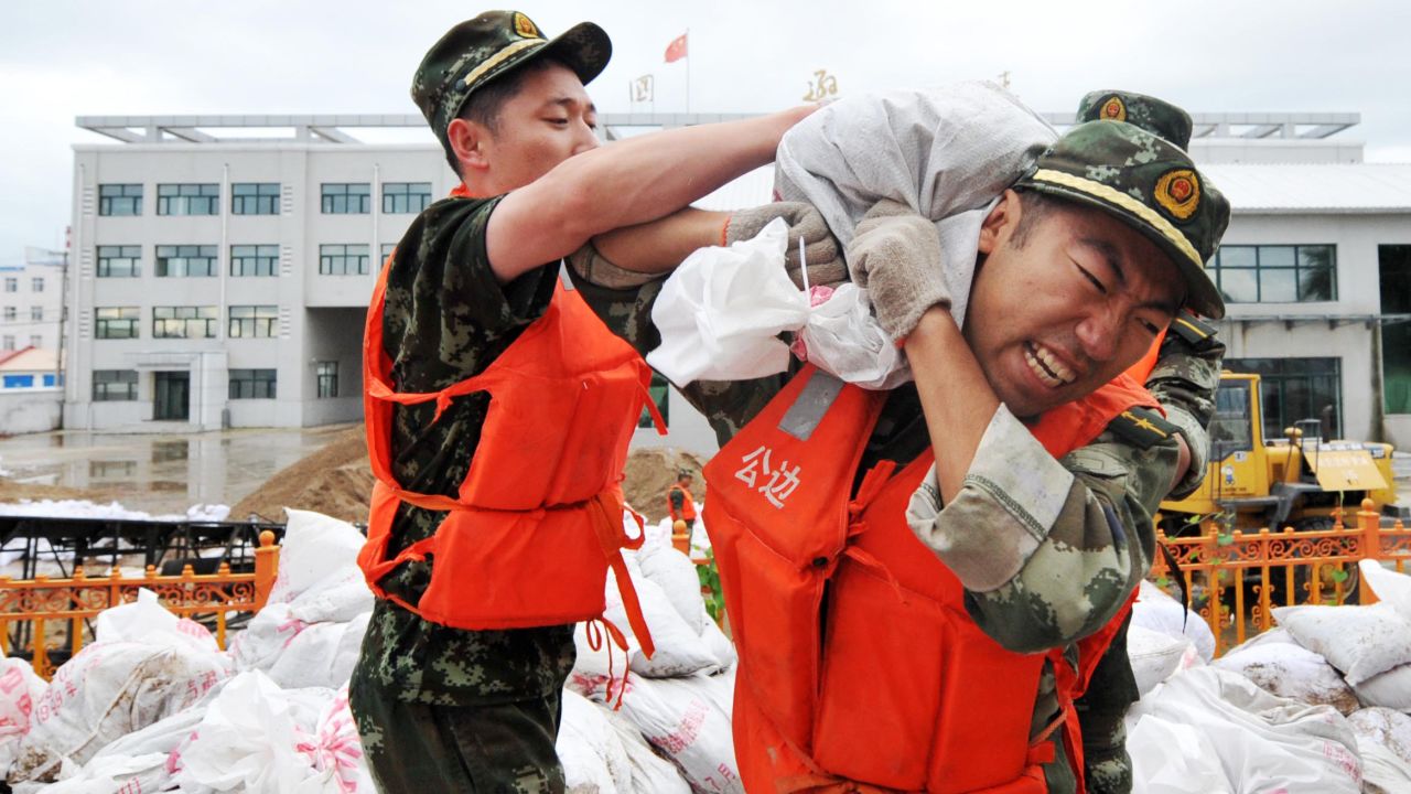 Soldiers carry sand bags for a barricade at the border crossing with Russia in Xunke County, China, on Saturday, August 17.