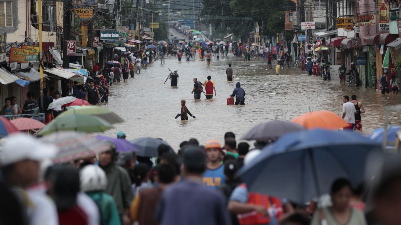People cross a flooded street to evacuate to higher ground in Marikina City on Tuesday, August 20.