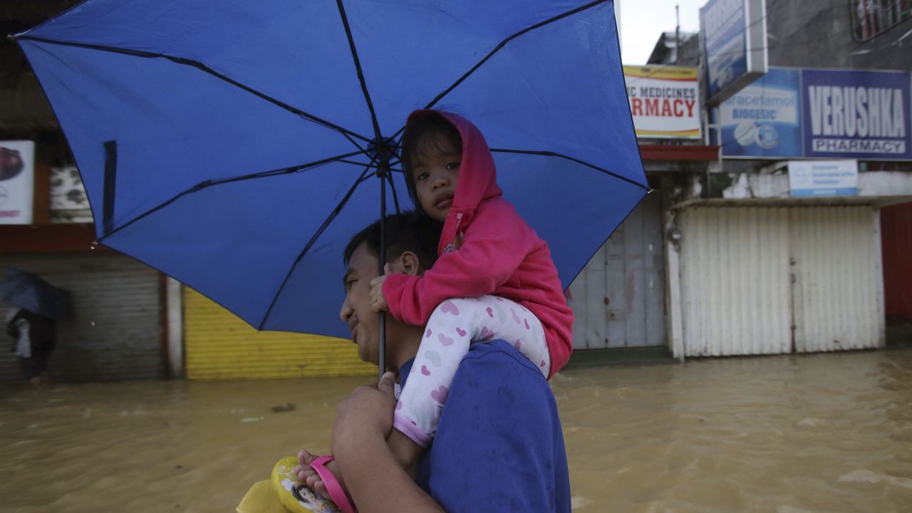 A man and a little girl evacuate to higher ground in Marikina City on August 20.