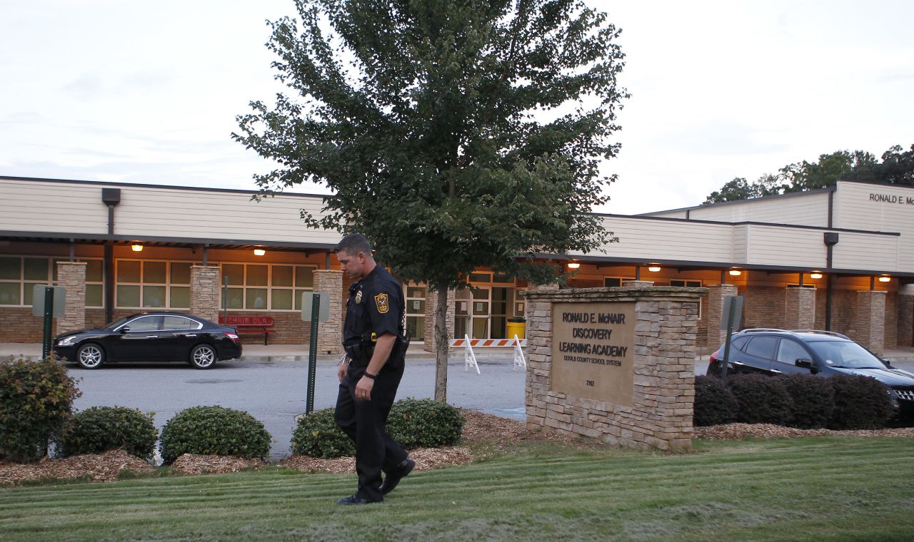 A policeman walks in front of Ronald E. McNair Discovery Learning Academy after a shooting incident in Decatur, Georgia, on Tuesday, August 20. Michael Brandon Hill, 20, opened fire at the school armed with an AK-47 "and a number of other weapons," police said. There were no reports of injuries.