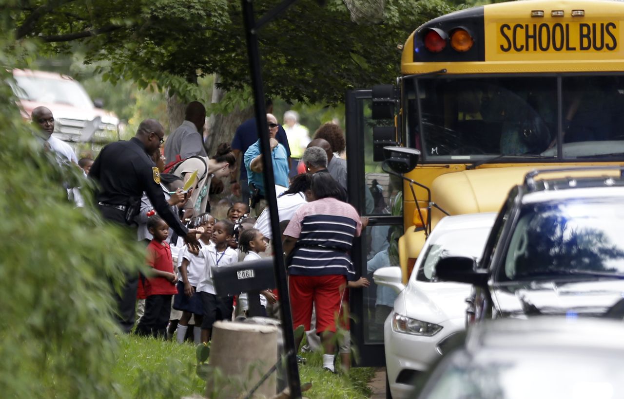 A police officer interacts with students as they board school buses to take them to reunite with their parents. 