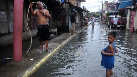 A man washes his face beside a flooded street in Kawit on August 21.