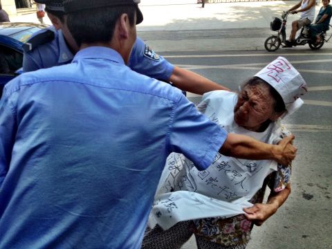 Police detain an elderly demonstrator on August 21 who was protesting against the Chinese justice system outside the court in Jinan.