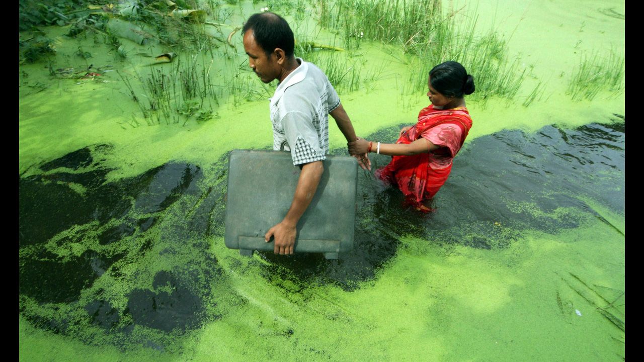 A couple wades through a waterlogged area following monsoon rains in Kolkata, India, on August 21. India's monsoon season, which runs from June through September, brings rains that are vital to agriculture, but which cause floods and landslides. 