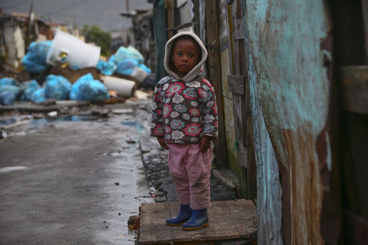 A girl looks from the door of her home in the flood affected Cape Town, South Africa, on August 21. Over the past two weeks, more than 4,000 residents living in informal settlements in Cape Town have been displaced due to a series of strong cold fronts causing heavy rains, flooding and gale force winds.
