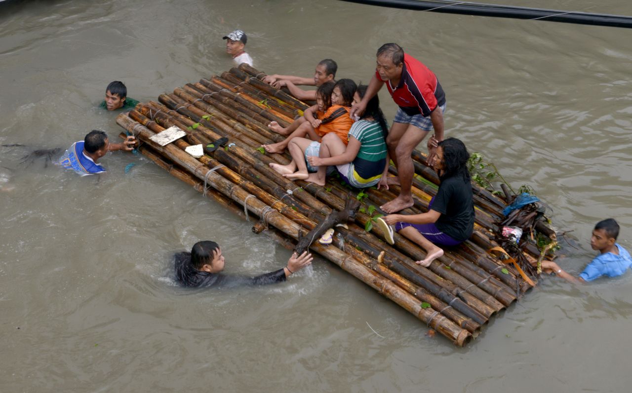 People ride on a bamboo raft over floodwaters in Noveleta, Philippines, on August 19. 