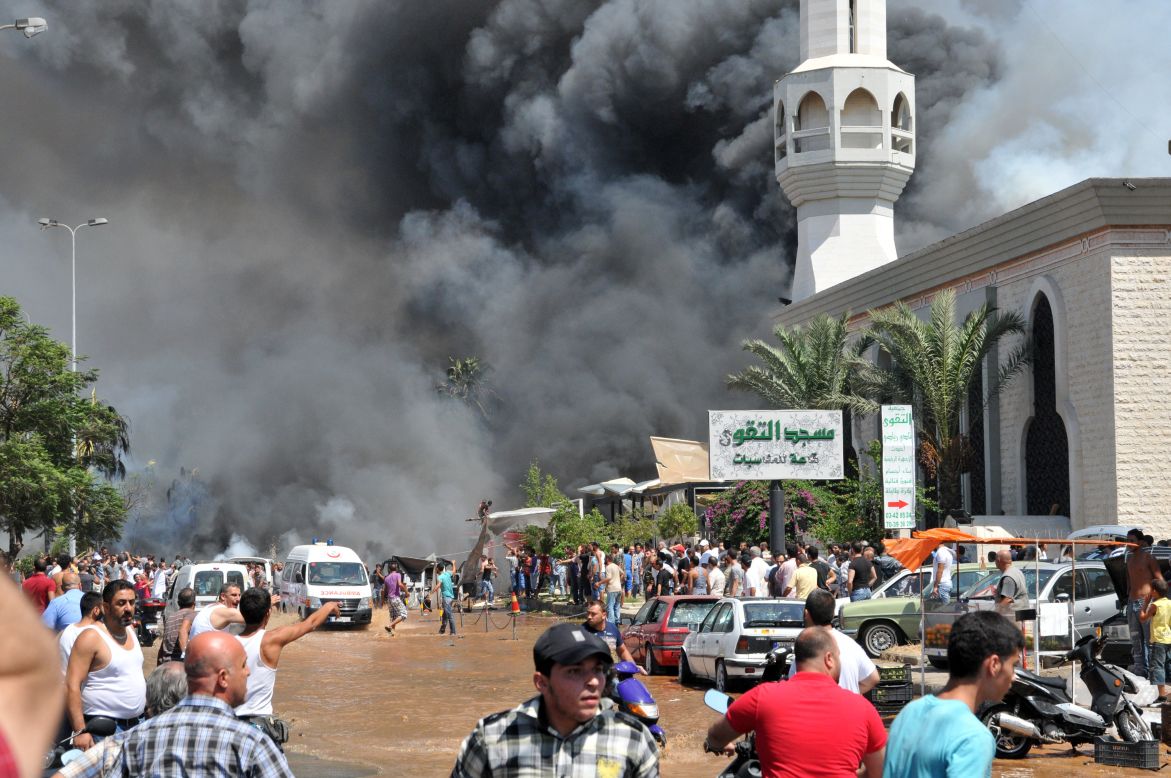 Smoke is seen above people gathering outside a mosque on the site of a powerful explosion in the northern Lebanese city of Tripoli on Friday, August 23. Two bombings killed dozens of people. The first blast occurred near a mosque led by a Sunni sheikh known for his links to Syrian rebels, Lebanon's state-run National News Agency said. The second occurred minutes later near another mosque, close to the residence of acting Prime Minister Najib Mikati.