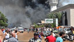 Smoke is seen above people gathering outside a mosque on the site of a powerful explosion in the northern Lebanese city of Tripoli on Friday, August 23. Two bombings killed dozens of people. The first blast occurred near a mosque led by a Sunni sheikh known for his links to Syrian rebels, Lebanon's state-run National News Agency said. The second occurred minutes later near another mosque, close to the residence of acting Prime Minister Najib Mikati.