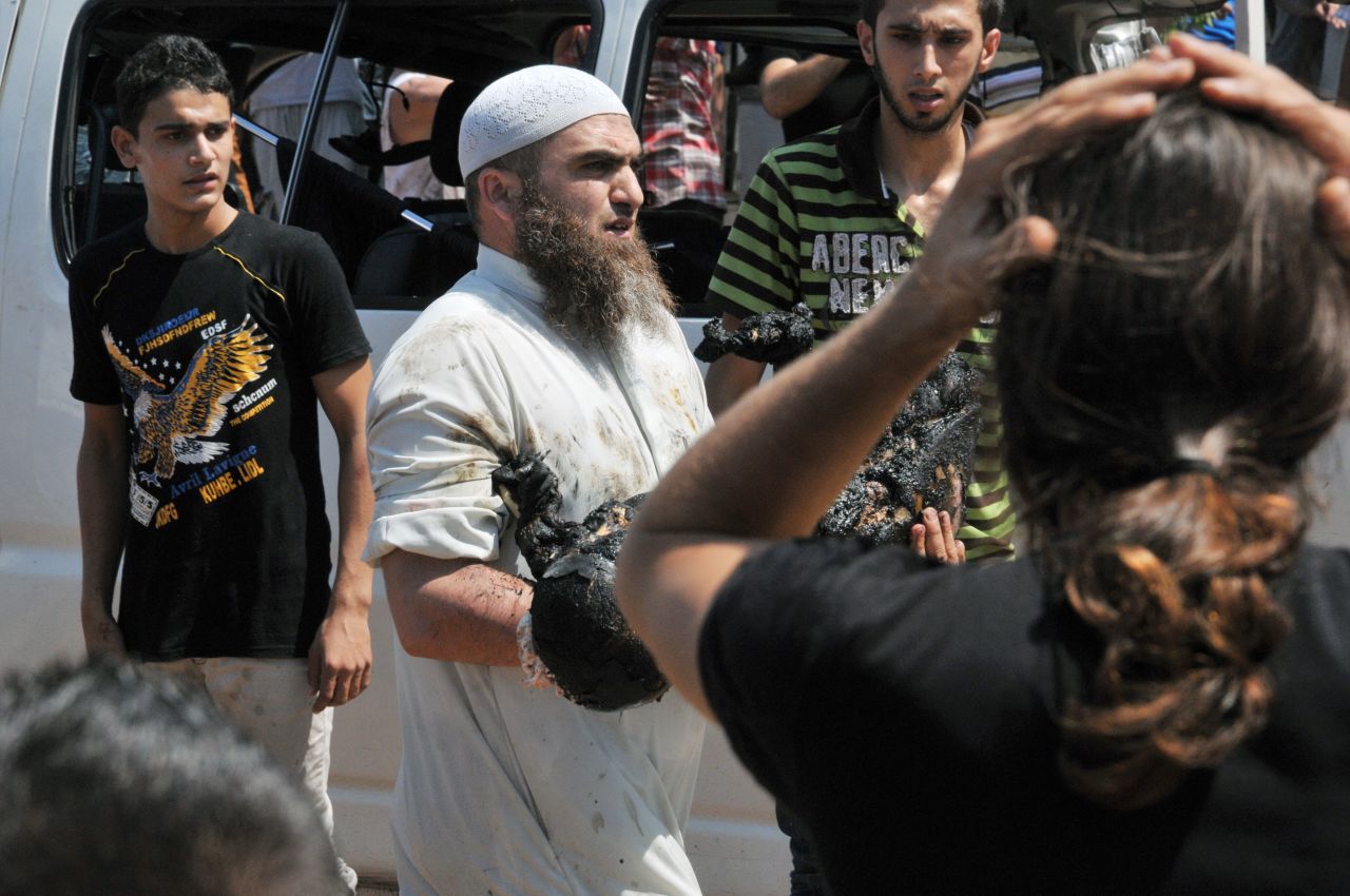 A man carries the burnt body of a victim of one of the explosions outside the al Taqwa mosque.