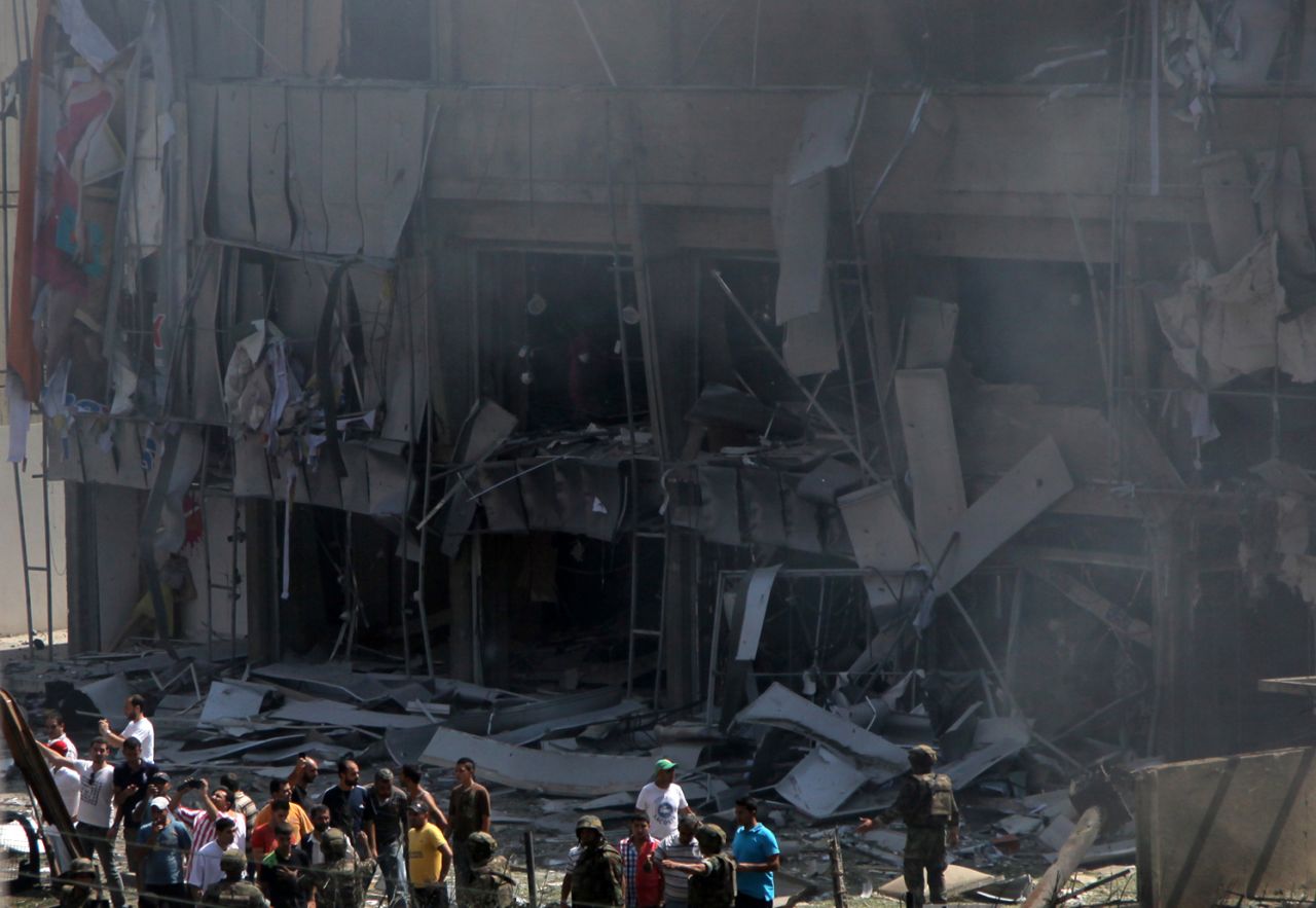 People stand in front of a severely damaged building as they gather outside the al Salam mosque.