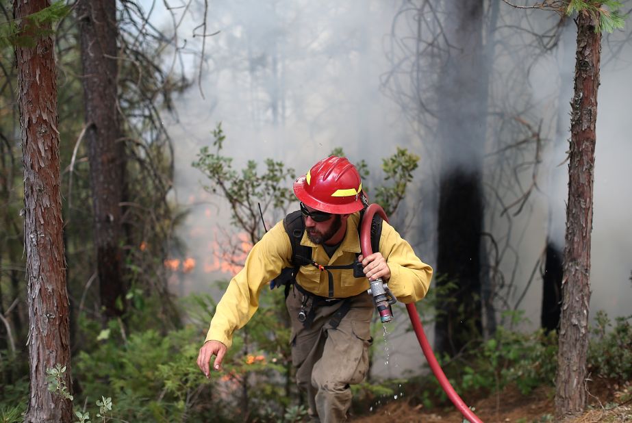 A firefighter from the Colorado-based South Arkansas Fire District carries a hose as he monitors the Rim Fire on August 22, in Groveland, California. 