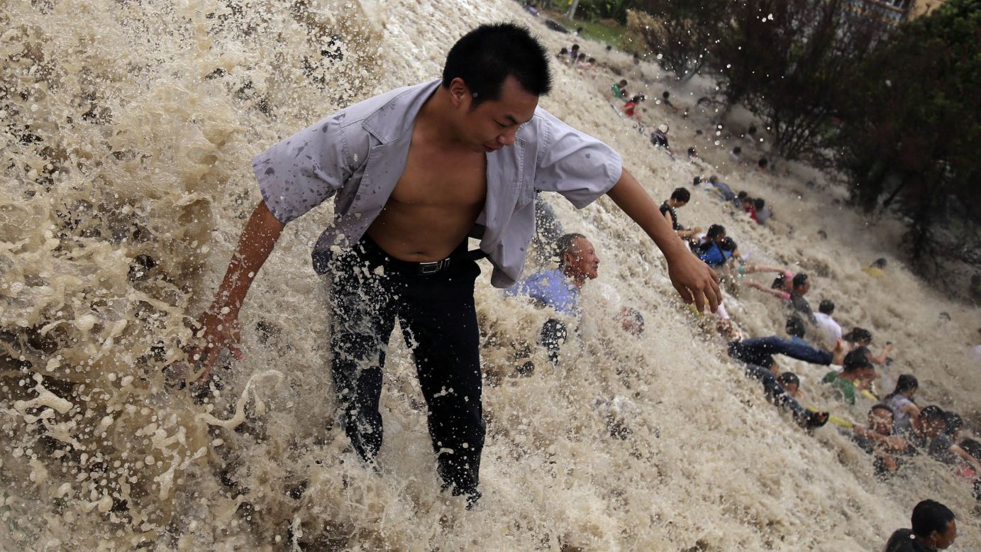 People are washed away on Thursday, August 22, by the huge waves of the "Haining tide" in Haining, China. Thirty were injured, according to state media. The tide is a daily occurrence when the Qiantang River tides hit the banks, but the waves surged higher than usual because of Typhoon Trami.