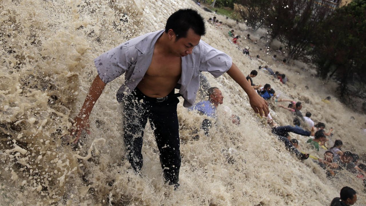 People are washed away on Thursday, August 22, by the huge waves of the "Haining tide" in Haining, China. Thirty were injured, according to state media. The tide is a daily occurrence when the Qiantang River tides hit the banks, but the waves surged higher than usual because of Typhoon Trami.