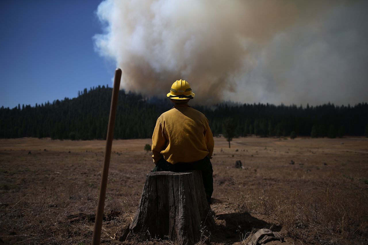 U.S. Fish and Wildlife Service firefighter Corey Adams sits on a tree stump as he monitors the Rim Fire near Groveland on August 25.