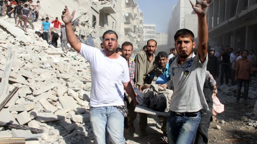 Syrian men evacuate a victim following an air strike by regime forces in the northern city of Aleppo on August 26, 2013.