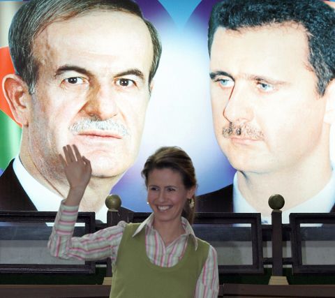 The Syrian first lady waves under a portrait of her husband, right, and his late father, former President Hafez al-Assad, during the opening ceremony of the Syrian Special Olympics in Damascus, Syria, on May 15, 2006.