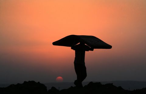 A Syrian Kurdish man carries a mattress at sunset at the Quru Gusik refugee camp in Iraq in August 2013.