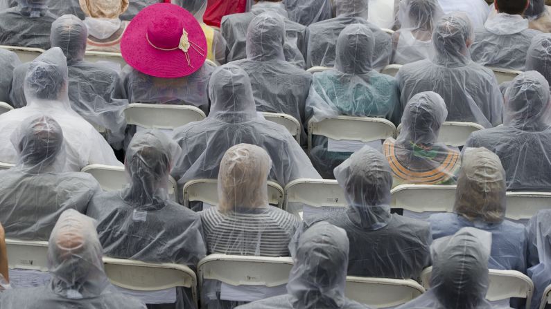 Attendees wear plastic rain ponchos as rain falls during the event. 
