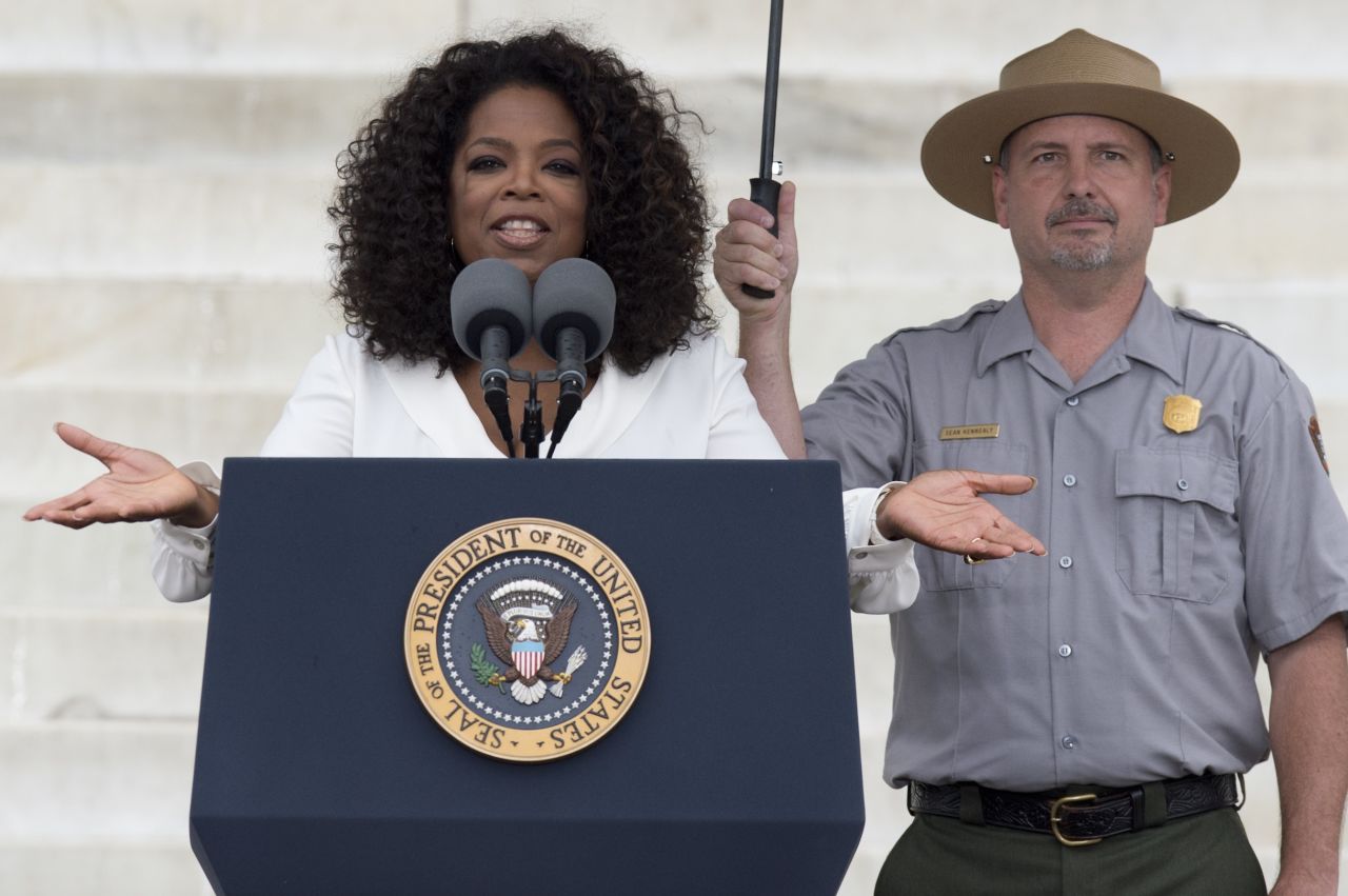 A park ranger holds an umbrella as Oprah Winfrey speaks during the event. 