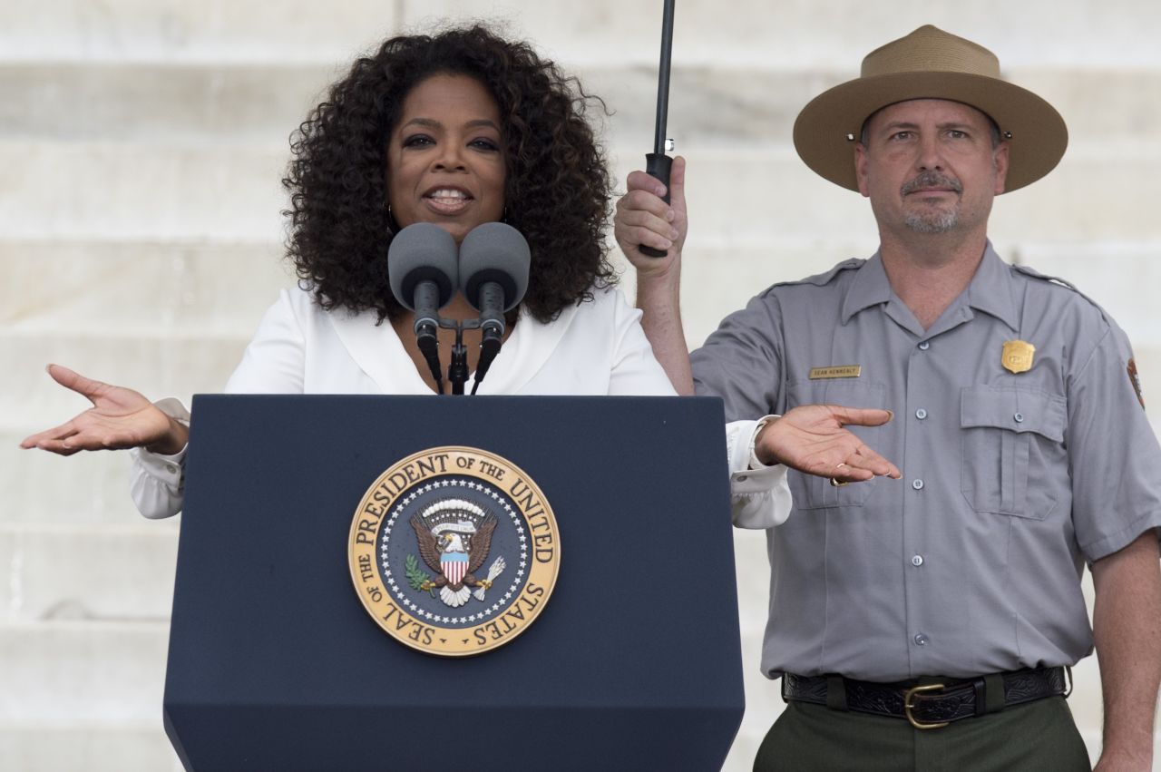 A park ranger holds an umbrella as Oprah Winfrey speaks during the event.