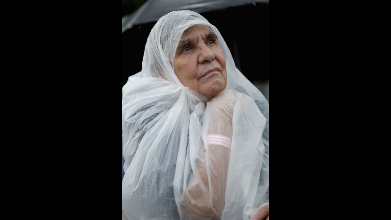 Undeterred by the rain, a covered woman listens to the speakers.