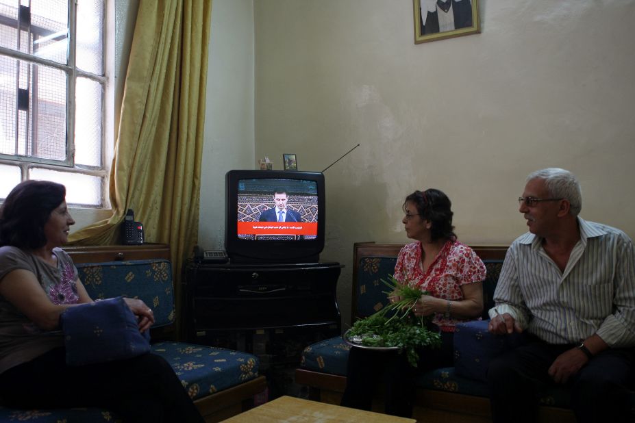Syrians listen to a televised speech by al-Assad in Damascus on June 3, 2012. Al-Assad said that his government faces a foreign plot to destroy Syria and blamed "monsters" for the Houla massacre in a rare televised speech delivered in parliament. 