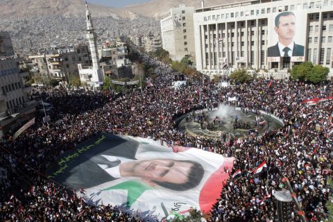 Syrian demonstrators carry a giant portrait of al-Assad in Damascus on November 28, 2011. Protesters waved Syrian flags and chanted nationalist songs in a demonstration against the Arab League's decision to impose crippling sanctions on the Assad regime.