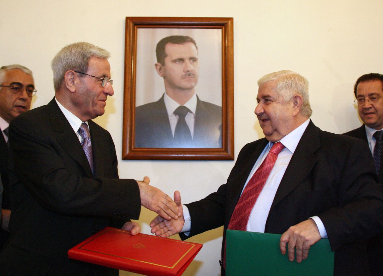 Syrian Foreign Minister Walid Muallem, right, and his Lebanese counterpart, Fawzi Salloukh, shake hands under a portrait of al-Assad in Damascus on October 15, 2008, after signing an agreement to restore diplomatic relations.