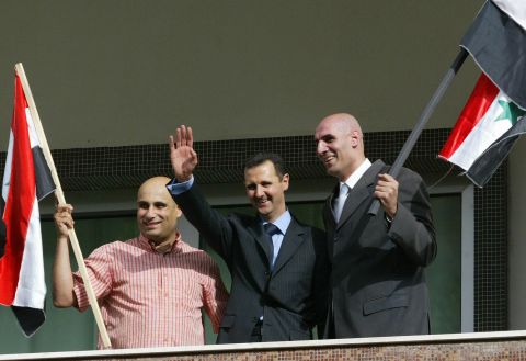 Two unidentified supporters of al-Assad join him on the balcony as he celebrates the referendum results in Damascus on May 29, 2007. Al-Assad won a second seven-year mandate after netting 97% of the vote in a referendum boycotted by the opposition.
