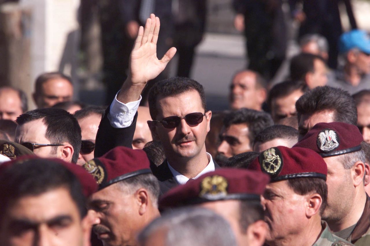 Al-Assad waves to supporters as he marches behind the coffin during his father's funeral in Damascus on June 13, 2000.