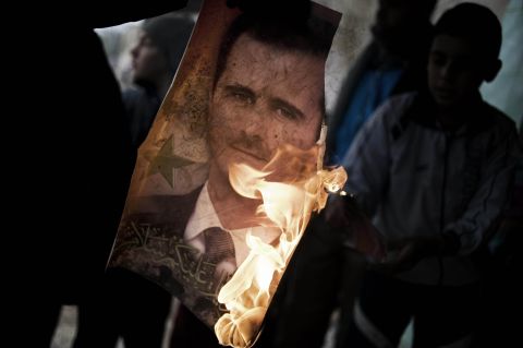 A member of the Free Syrian Army holds a burning portrait of al-Assad near the flashpoint city Homs on January 25, 2012.