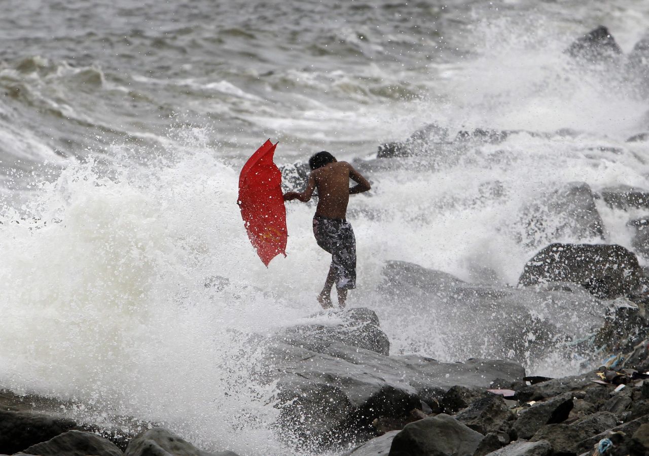 A Filipino boy braves strong waves as he crosses a breakwater in Pasay, Philippines, on Tuesday, August 27.