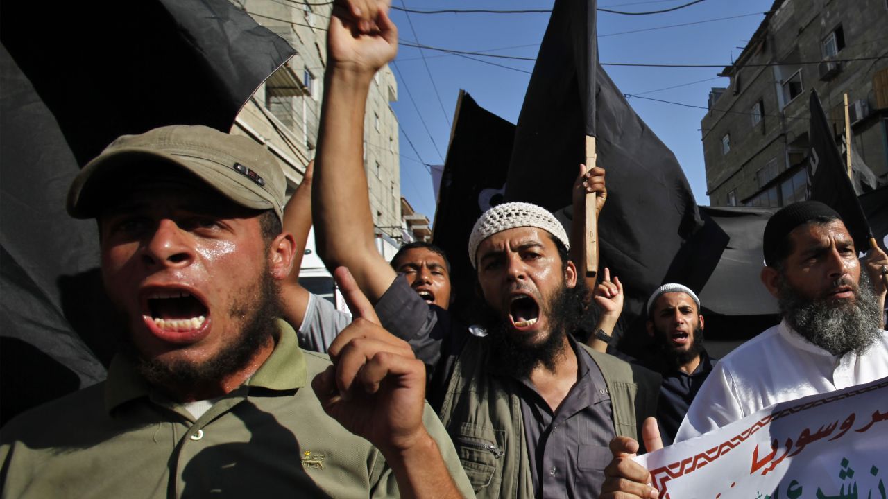 Palestinian members from Youth Salafists group chant slogans while waving their black flags during a protest against the Egyptian and Syria regimes in Rafah Refugee Camp, southern Gaza Strip, Thursday, Aug. 22, 2013. Arabic on poster reads "Criminals and murderers". Syrian government forces pressed their offensive in eastern Damascus on Thursday, bombing rebel-held suburbs where the opposition said the regime had killed more than 100 people the day before in a chemical weapons attack. The government has denied allegations it used chemical weapons in artillery barrages on the area known as eastern Ghouta on Wednesday as "absolutely baseless. (AP Photo/Adel Hana)