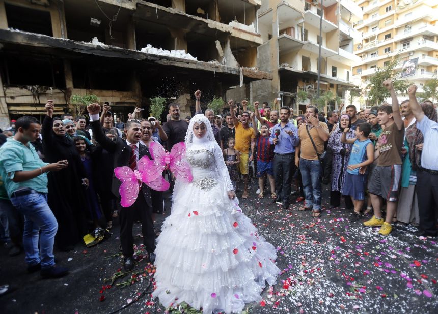 A crowd cheers as a Lebanese bride and groom pose for pictures at the site of a car bomb just days before in Beirut, Lebanon.