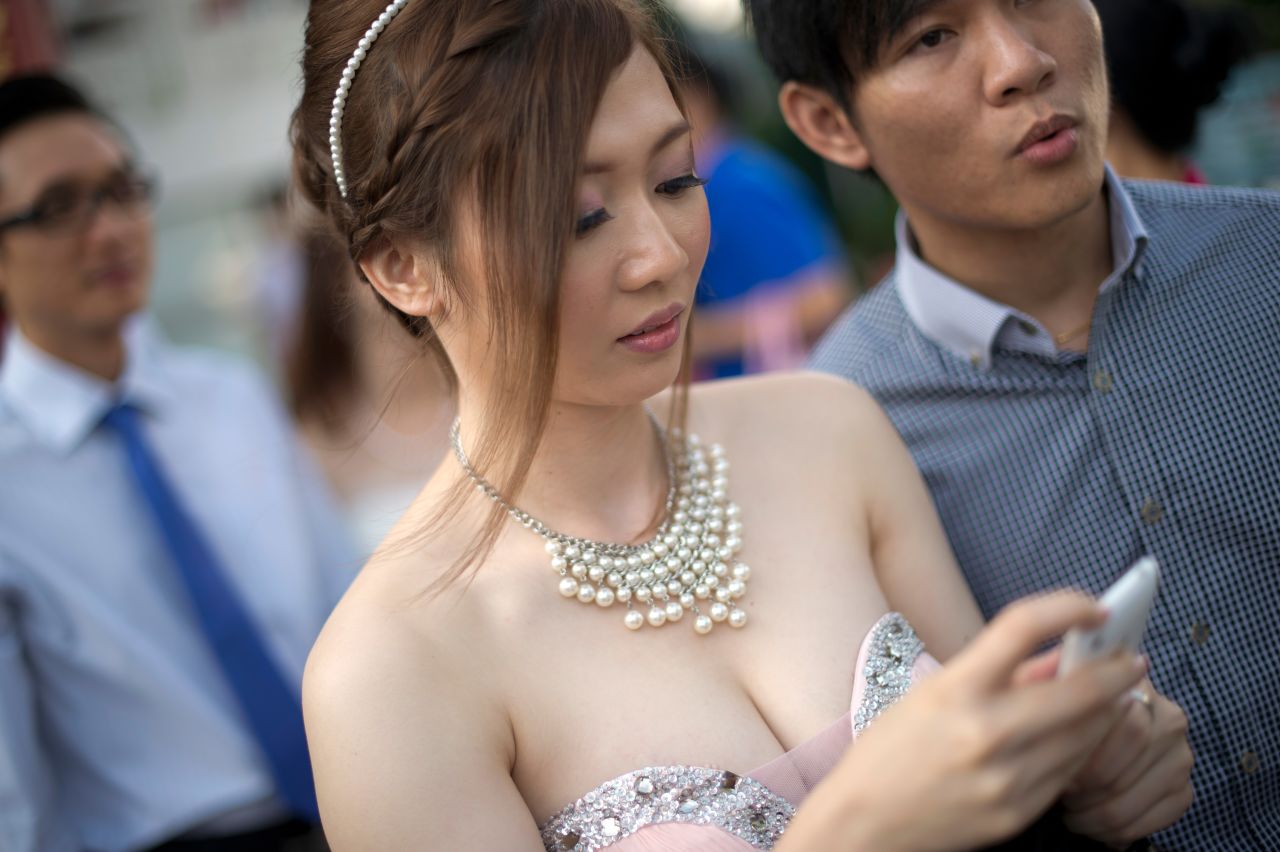 A bride checks her messages while getting ready for a group picture after a mass wedding outside a Chinese temple in Kuala Lumpur on December 12, 2012.