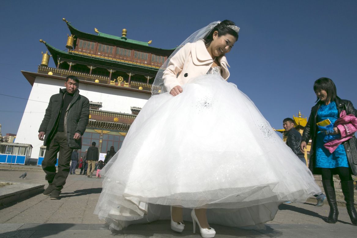 A bride walks holding her wedding dress at the Gandan monastery on October 18, 2012, a special day on the lunar calendar for wedding ceremonies, in Ulaanbaatar, Mongolia.