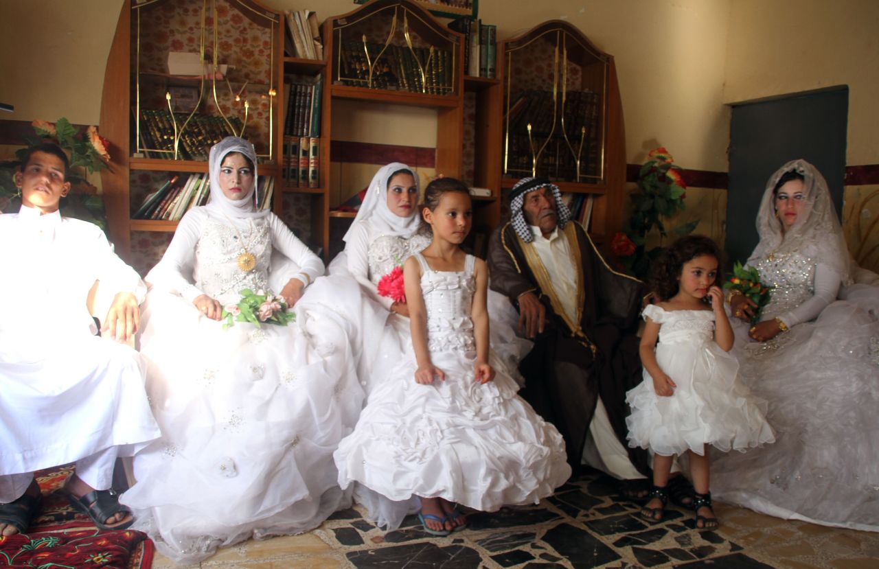 Musali Mohammed al-Mujamaie, a 92-year-old Iraqi farmer, sits next to Muna Mukhlif al-Juburi, his new 22-year-old wife, the new wives of his grandsons and one of his grandsons during celebrations after their group wedding in his home village of Gubban, Iraq.