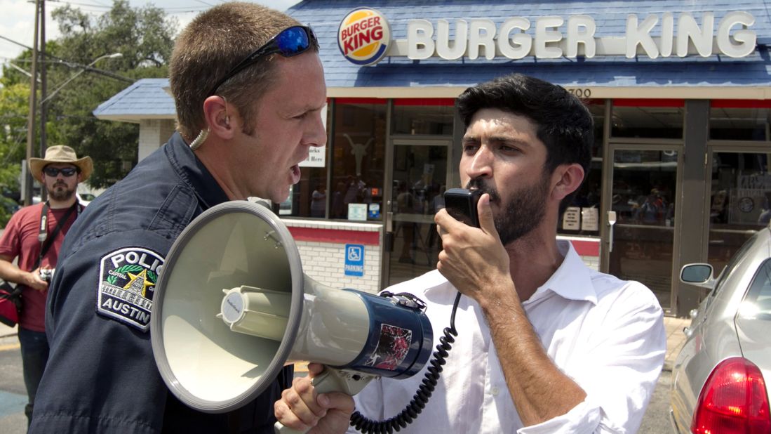 A police officer orders Greg Casar of the Workers Defense Project to get off the property of a Burger King in Austin, Texas, on  August 29, 2013. Casar was leading a group of about 200 people supporting the nationwide fast food strike. Fast food workers in 60 cities across the country walked off the job in a protest for higher wages.