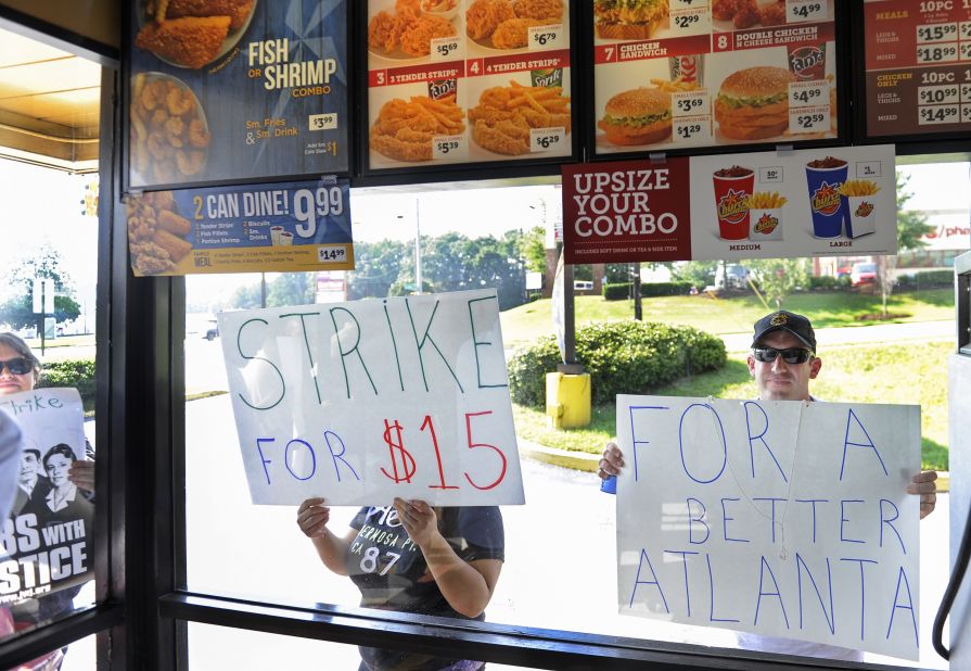 Demonstrators hold signs up to the window of a Church's Chicken in Atlanta on August 29. Workers and their supporters were calling on fast food chains to pay a minimum of $15 an hour.