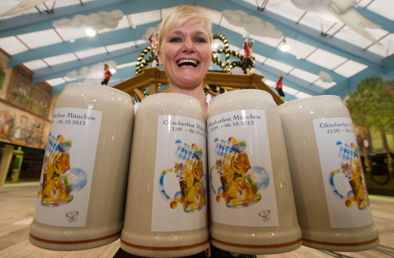 Waitress Kathi holds four beer mugs for the coming Oktoberfest event .
