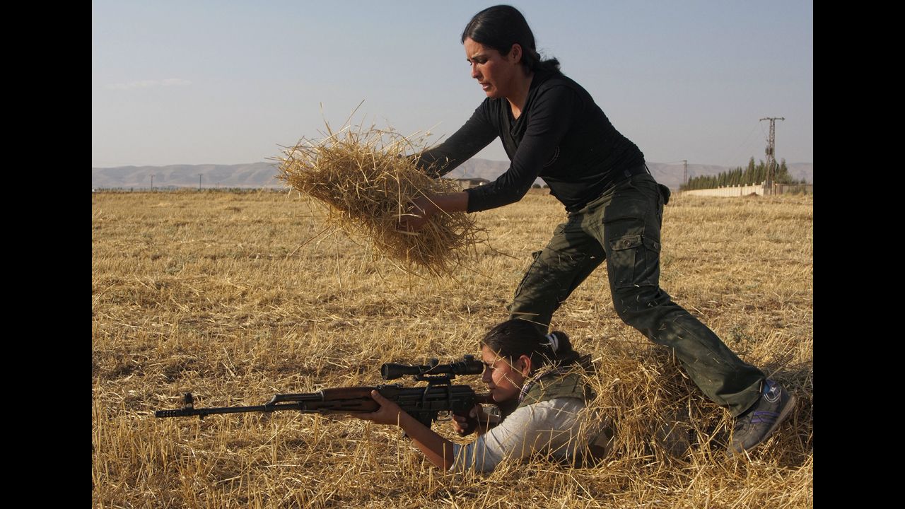 A Syrian Kurd uses hay to hide another woman in a training session organized by the Kurdish Women's Defense Units on Wednesday, August 28, in a northern Syrian border village. They're preparing if the area comes under attack. 