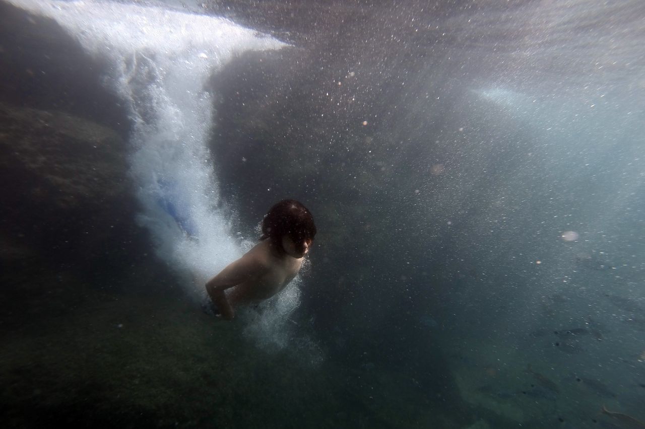 A boy dives in a creek near the village of Portofino, Italy, during the Italian summer holidays, on Sunday, August 25.