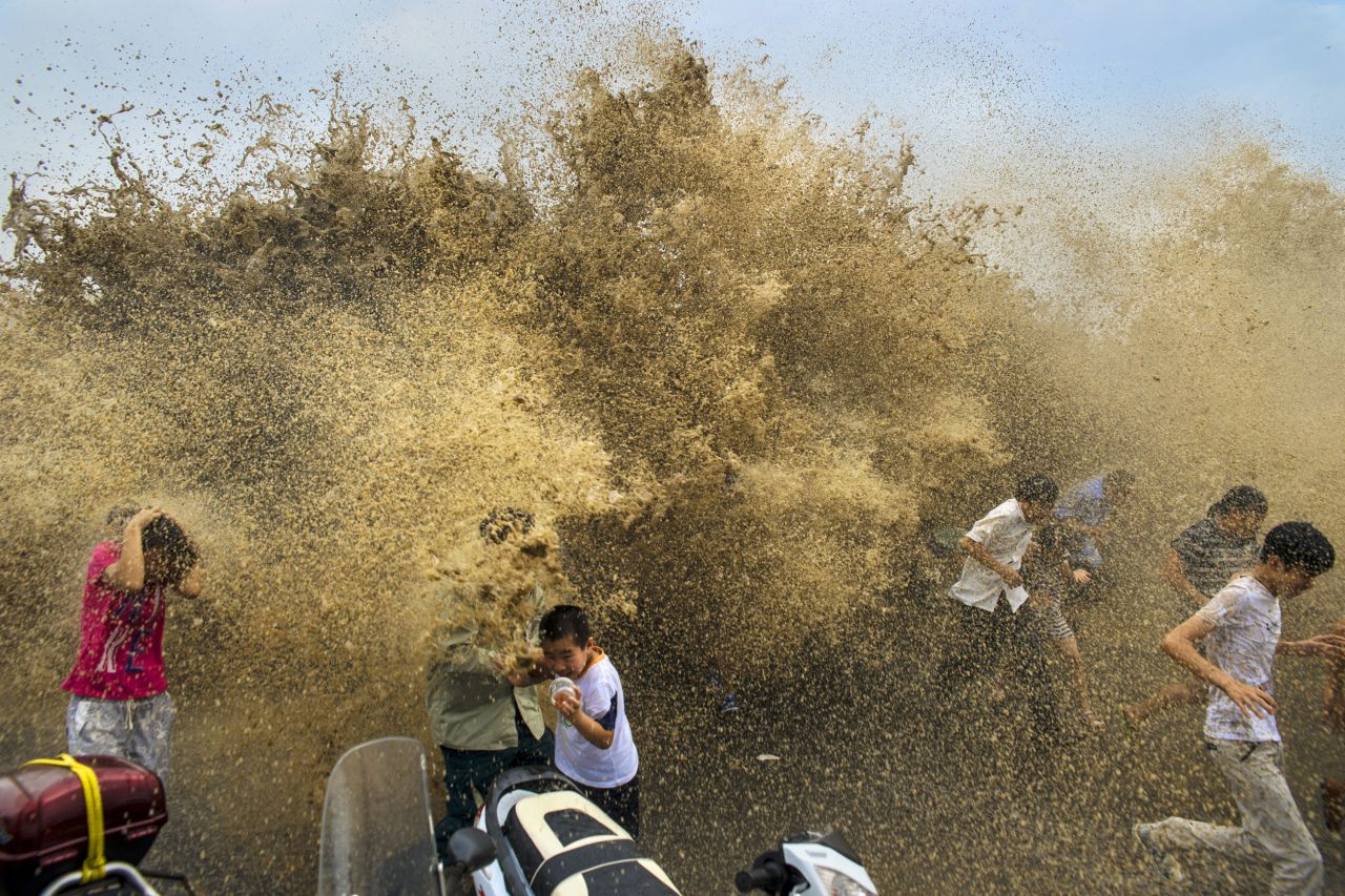 People run away from waves from a tidal bore as it surges past a barrier on the banks of the Qiantang River, in Hangzhou, China, on August 25.