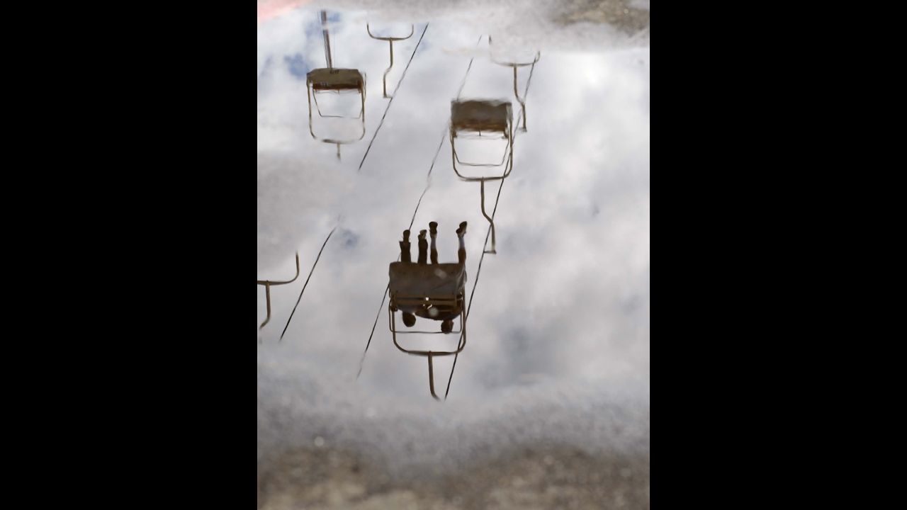 Fair lift riders are reflected in a puddle caused by the rain that fell on the seventh day of the Oregon State Fair, in Salem, Oregon, on Thursday, August 29.